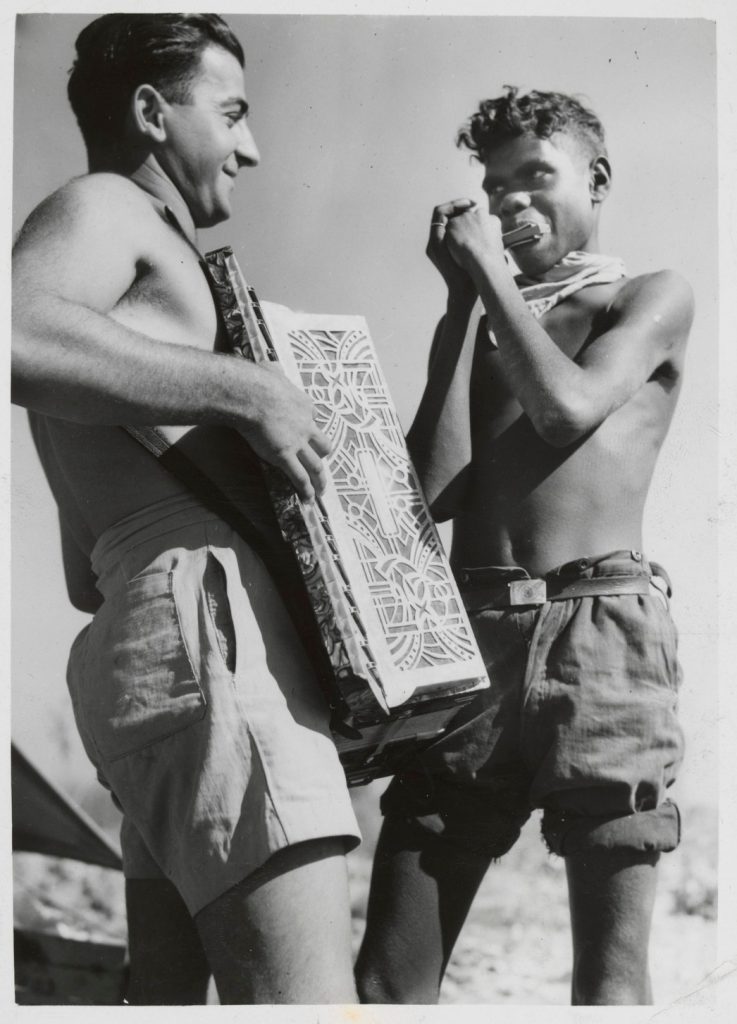 L. Lopata playing the piano accordion and an Aboriginal worker playing mouth organ